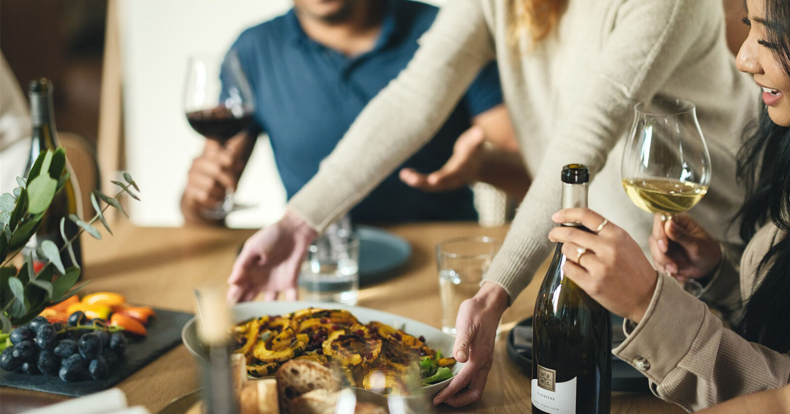 A dish being served at a dinner party with bottles of WillaKenzie wine.